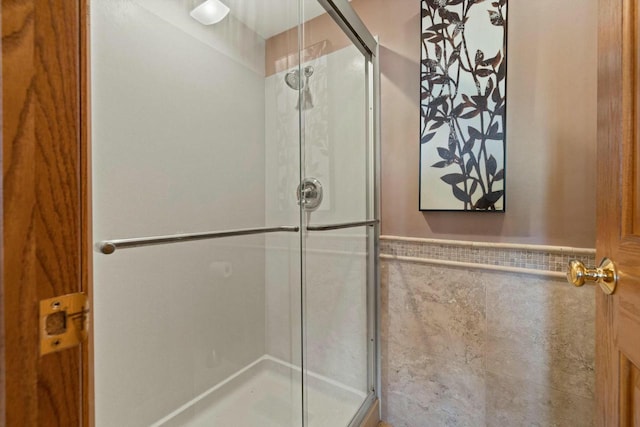 bathroom featuring tile walls and a shower with shower door