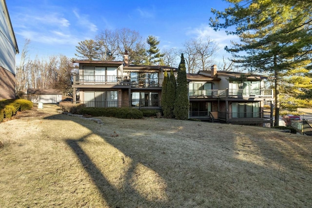 back of house featuring a lawn and a balcony