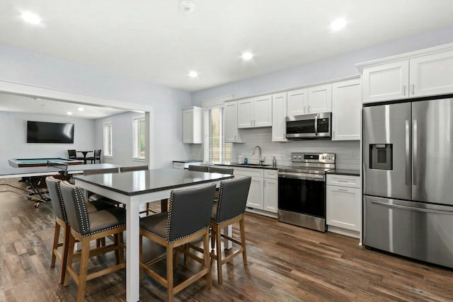 kitchen featuring sink, dark wood-type flooring, appliances with stainless steel finishes, white cabinets, and decorative backsplash