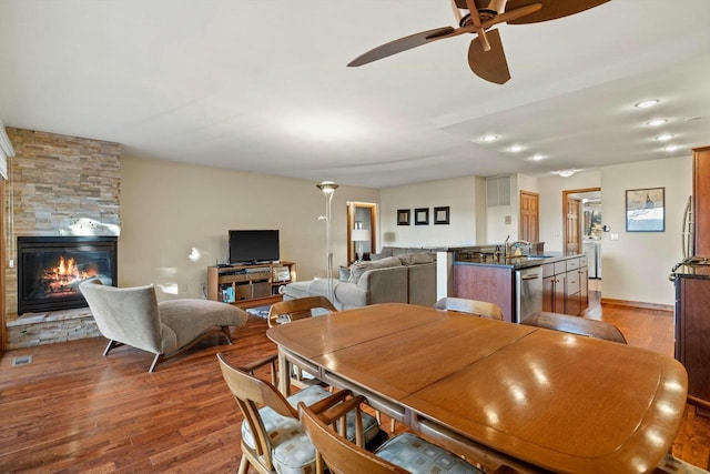 dining space with washer / clothes dryer, a fireplace, ceiling fan, and light wood-type flooring