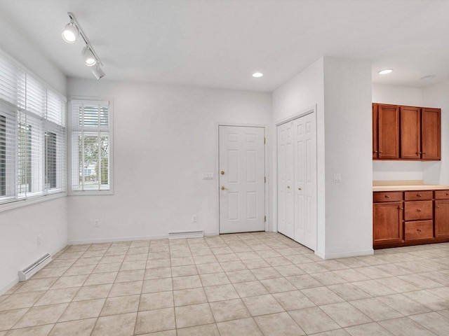 empty room with a baseboard radiator, light tile patterned floors, and track lighting