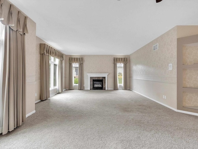 unfurnished living room with a premium fireplace and carpet flooring