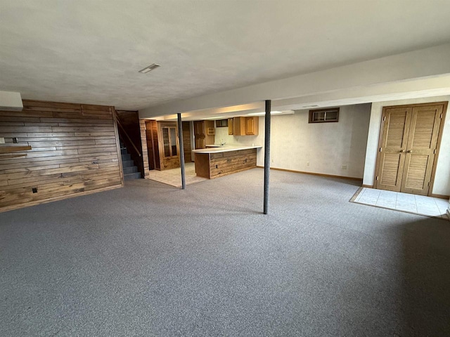 finished below grade area featuring baseboards, wood walls, stairway, and light colored carpet