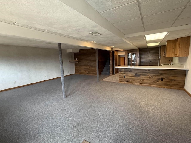 interior space with a drop ceiling, light carpet, a sink, baseboards, and stairs