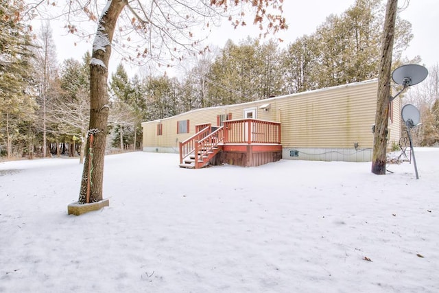 snow covered back of property with a deck