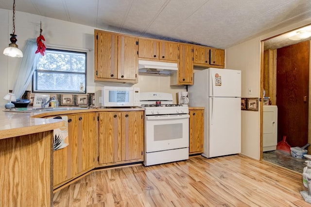 kitchen featuring pendant lighting, washer / clothes dryer, sink, light hardwood / wood-style floors, and white appliances