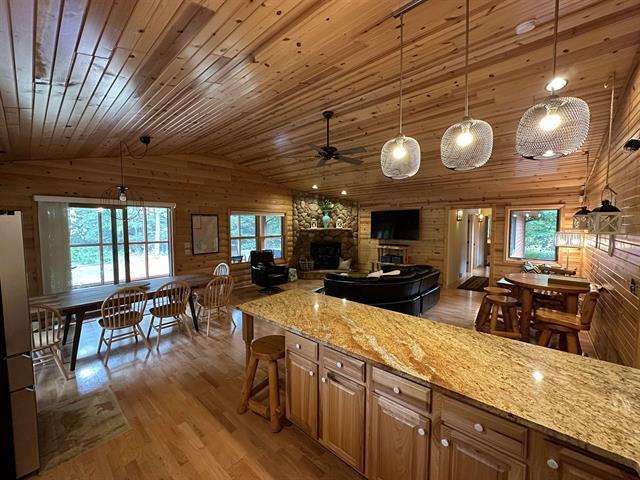 kitchen with pendant lighting, hardwood / wood-style floors, wooden walls, and light stone countertops