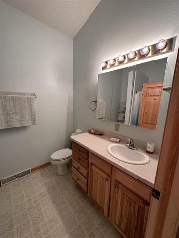 bathroom with vanity, toilet, vaulted ceiling, and a textured ceiling