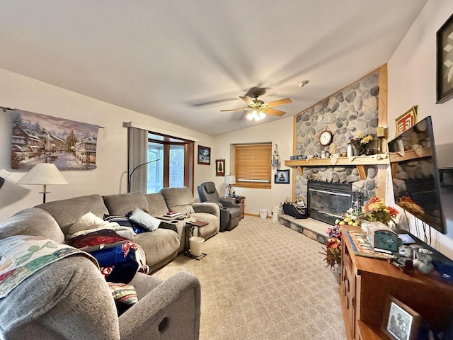 carpeted living room featuring lofted ceiling, a stone fireplace, and ceiling fan