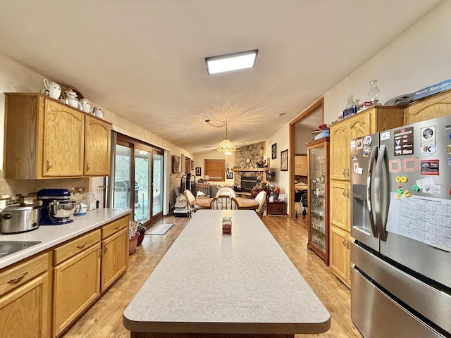 kitchen featuring lofted ceiling, a center island, pendant lighting, and stainless steel fridge