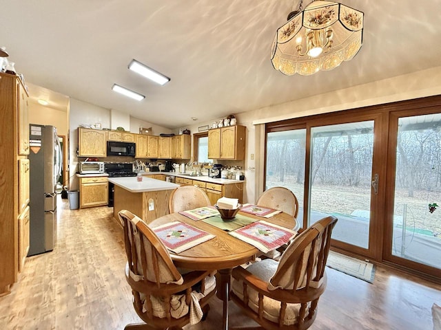 dining area with an inviting chandelier, sink, vaulted ceiling, and light hardwood / wood-style flooring