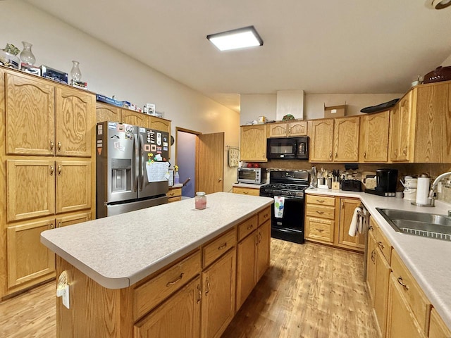 kitchen featuring lofted ceiling, sink, a center island, black appliances, and light wood-type flooring