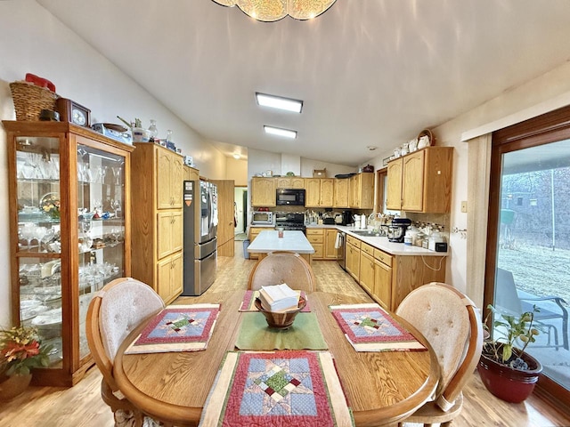 dining area with lofted ceiling, sink, and light hardwood / wood-style flooring