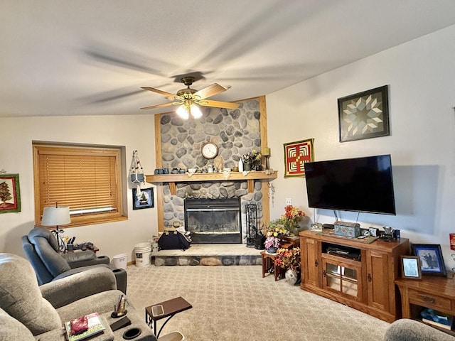 carpeted living room featuring a stone fireplace and ceiling fan