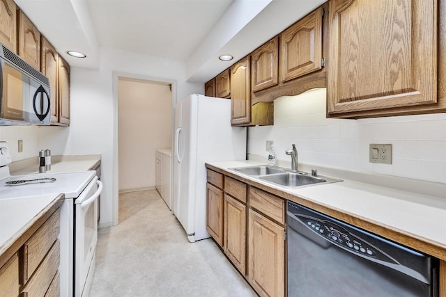 kitchen with sink, backsplash, black appliances, and washing machine and dryer