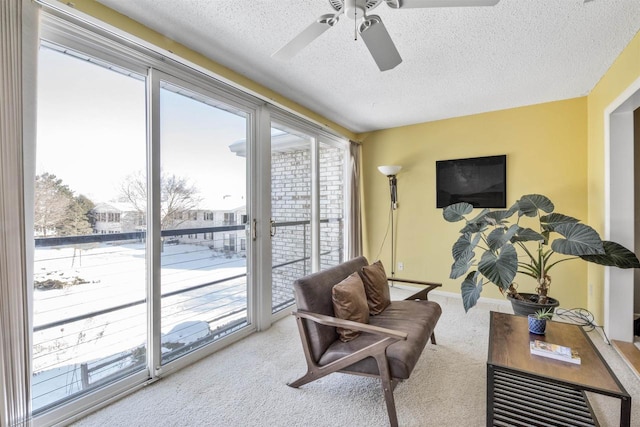 living area featuring ceiling fan, light carpet, and a textured ceiling