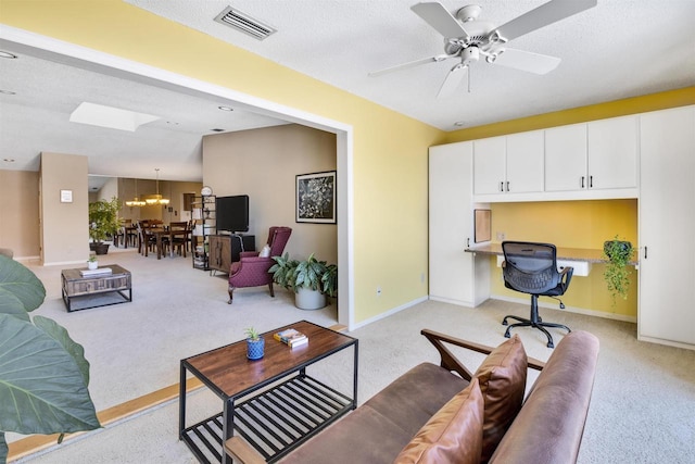 carpeted living room featuring ceiling fan, built in desk, and a textured ceiling