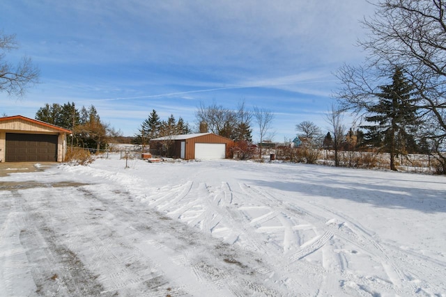 yard layered in snow featuring a garage and an outdoor structure