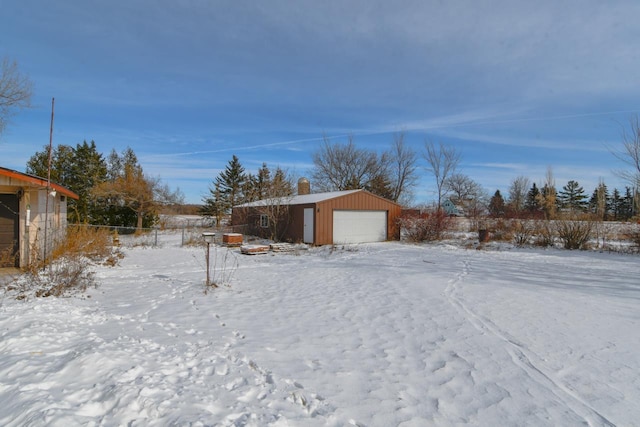 snowy yard featuring a garage and an outdoor structure