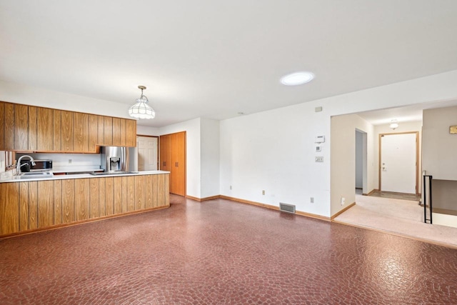 kitchen with stainless steel refrigerator with ice dispenser, sink, pendant lighting, and kitchen peninsula