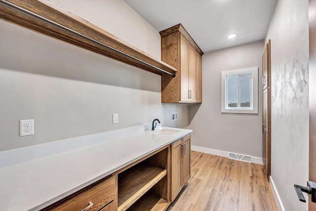 laundry room with cabinets, washer hookup, sink, and light hardwood / wood-style flooring