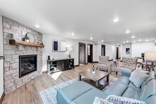 living room with a stone fireplace and light hardwood / wood-style floors