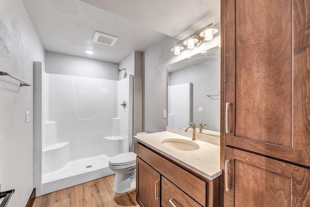 bathroom with toilet, hardwood / wood-style floors, vanity, and walk in shower