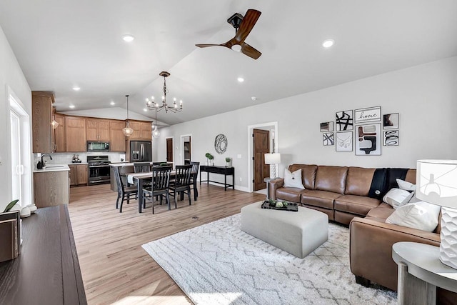 living room featuring ceiling fan with notable chandelier, lofted ceiling, sink, and light hardwood / wood-style floors