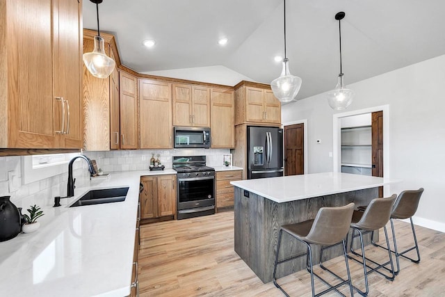 kitchen featuring appliances with stainless steel finishes, decorative light fixtures, sink, and a kitchen island