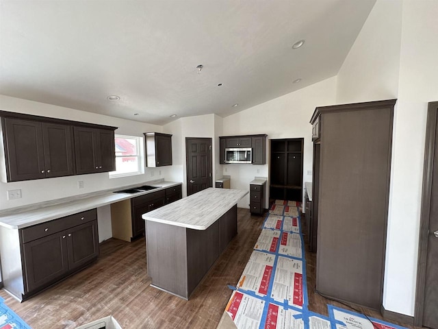 kitchen with lofted ceiling, dark brown cabinets, black electric cooktop, dark hardwood / wood-style floors, and a kitchen island