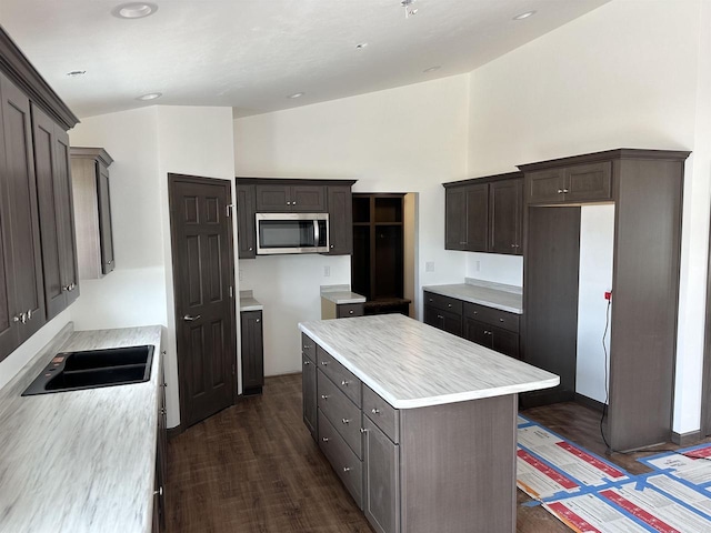 kitchen with sink, high vaulted ceiling, dark hardwood / wood-style floors, dark brown cabinetry, and a kitchen island