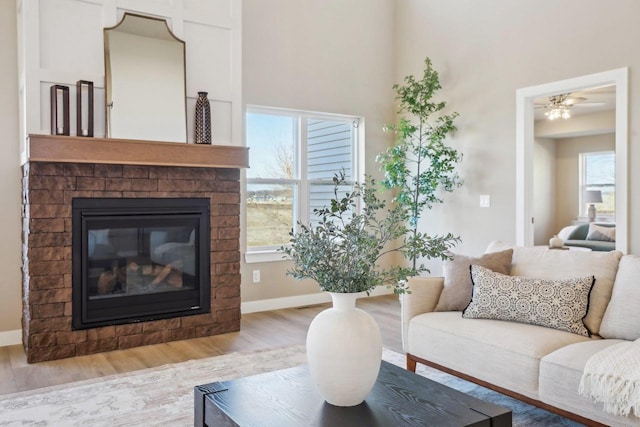 living room featuring a fireplace, light wood-type flooring, and baseboards