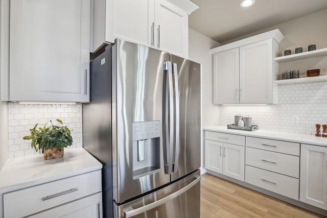 kitchen with stainless steel refrigerator with ice dispenser, open shelves, white cabinetry, light wood-style floors, and light countertops