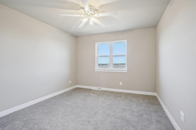 carpeted spare room featuring visible vents, baseboards, and ceiling fan