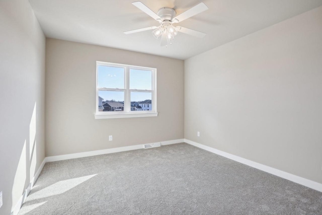 carpeted spare room featuring visible vents, a ceiling fan, and baseboards