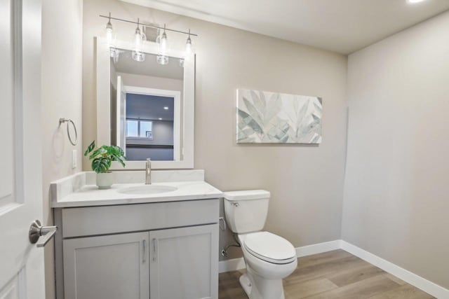 bathroom featuring vanity, toilet, wood finished floors, and baseboards