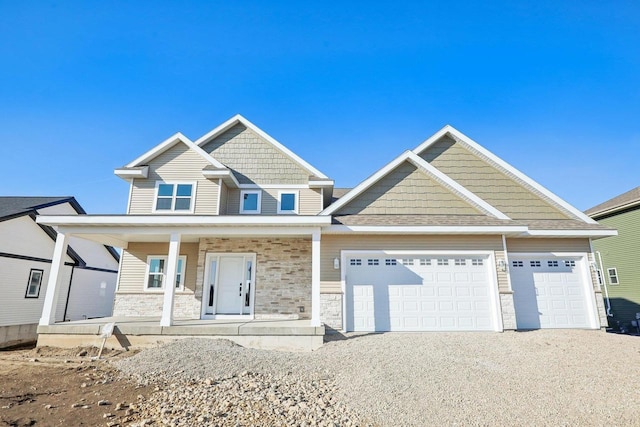 craftsman-style home featuring a garage, stone siding, covered porch, and driveway