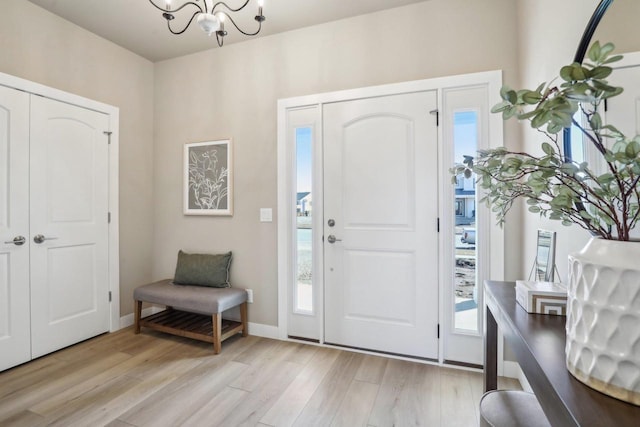 foyer featuring light wood finished floors, baseboards, and an inviting chandelier