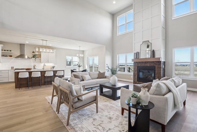 living area with light wood-style flooring, a fireplace, baseboards, and a healthy amount of sunlight