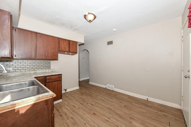 kitchen featuring sink, decorative backsplash, and light hardwood / wood-style flooring