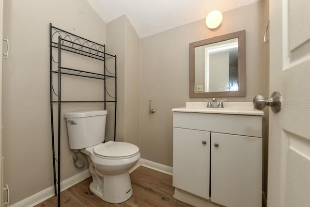 bathroom featuring vanity, hardwood / wood-style floors, vaulted ceiling, and toilet