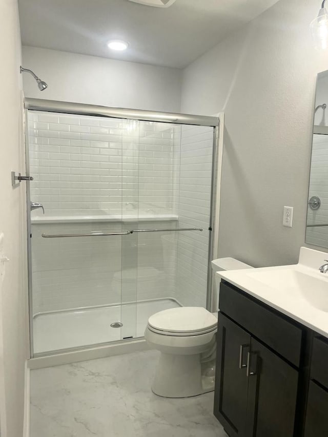 bathroom with walk in shower, vanity, and toilet