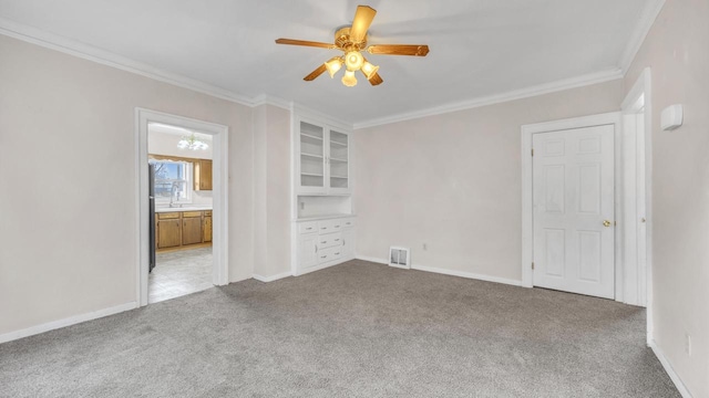 carpeted empty room with ceiling fan, ornamental molding, and sink