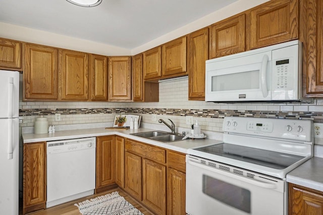 kitchen featuring white appliances, sink, and backsplash