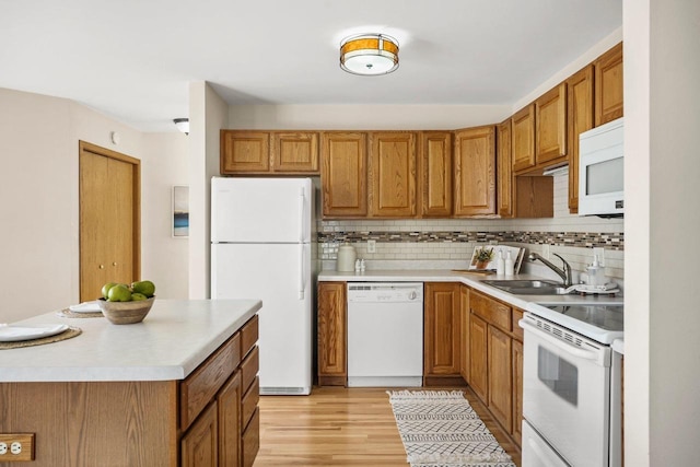 kitchen featuring sink, white appliances, tasteful backsplash, and light wood-type flooring