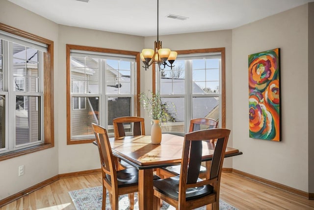 dining space with light wood-type flooring and an inviting chandelier