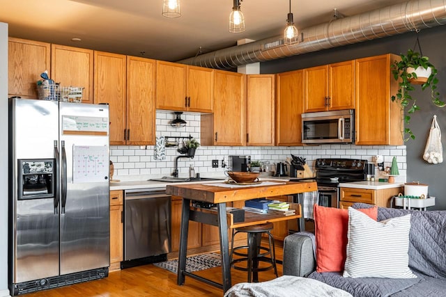 kitchen featuring pendant lighting, stainless steel appliances, sink, and tasteful backsplash