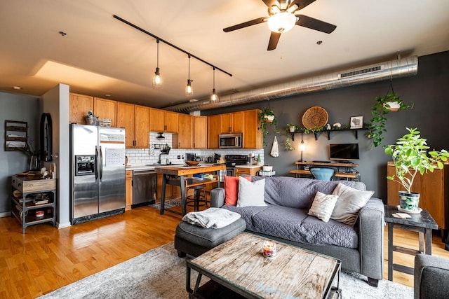 living room with ceiling fan and light wood-type flooring