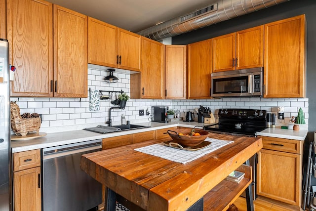 kitchen featuring stainless steel appliances, butcher block counters, sink, and decorative backsplash