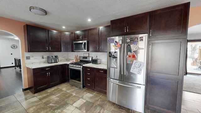 2930 Youngdale Ave, La Crosse, WI 54603 - kitchen with backsplash, dark brown cabinets, stainless steel appliances, light stone counters, and a textured ceiling